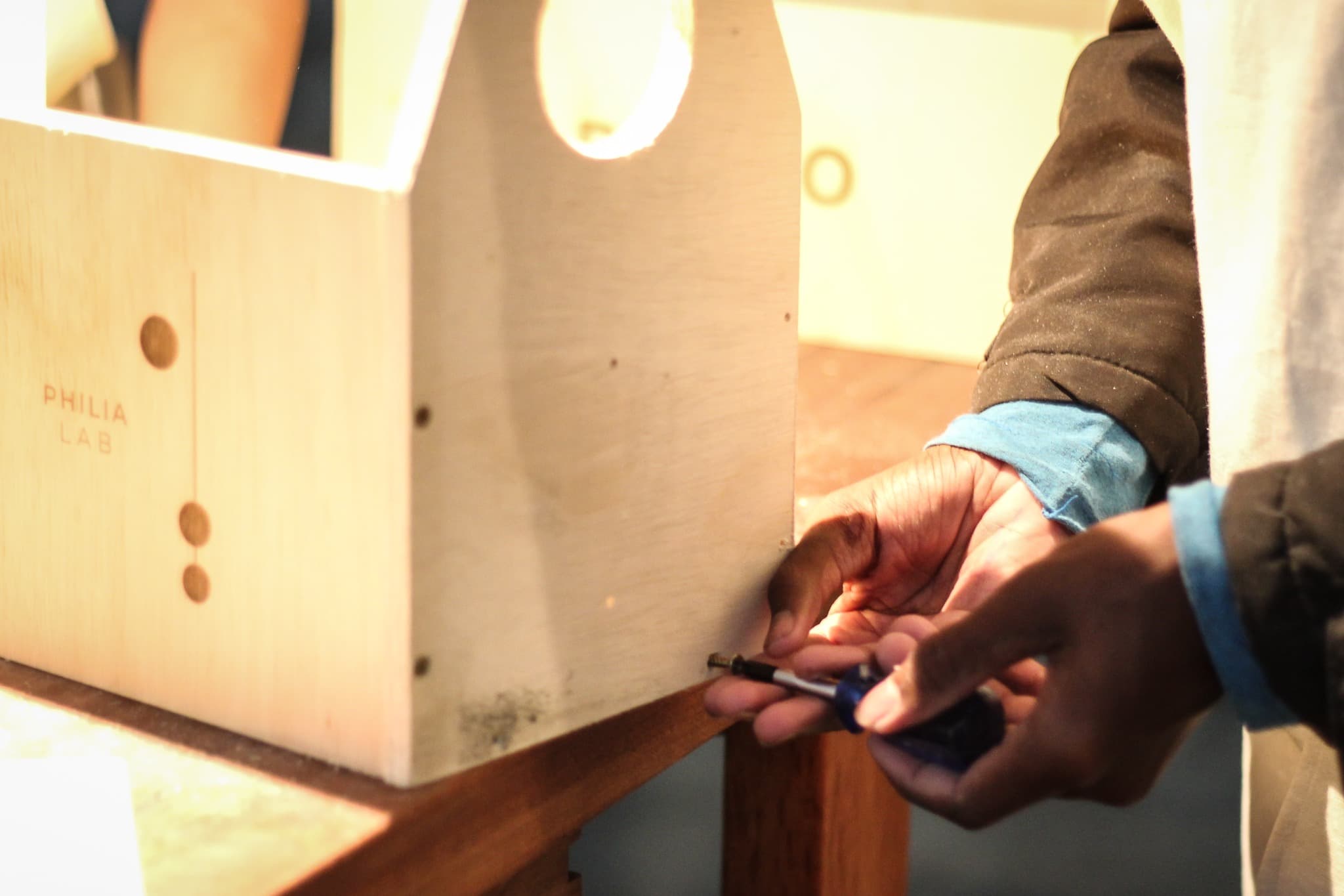 Hands assembling a PHILIA LAB wooden object